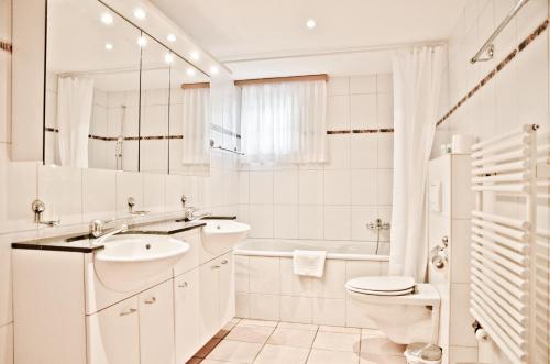 ein weißes Bad mit einem Waschbecken und einem WC in der Unterkunft Apartment St. Louis 3.5 - GriwaRent AG in Grindelwald