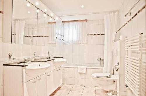 a white bathroom with a sink and a toilet at Apartment St. Louis 3.5 - GriwaRent AG in Grindelwald