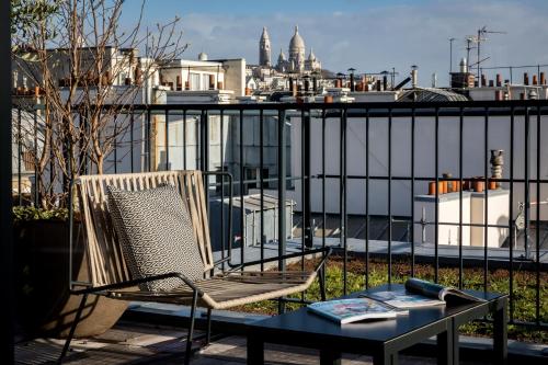 a chair and table on a balcony with a view of the city at Laz' Hotel Spa Urbain Paris in Paris