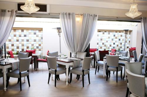 a dining room with tables and chairs and windows at Oleander Guest House in Kimberley