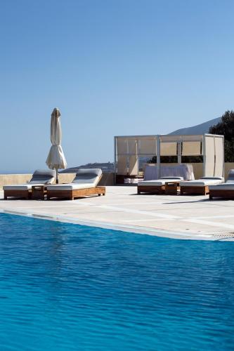 a pool with chaise lounge chairs and a swimming pool at The Majestic Hotel in Fira