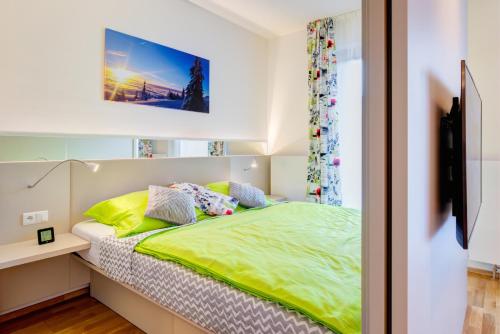 a bedroom with a bed with green sheets and a tv at Apartman Medvědín 307 in Špindlerův Mlýn