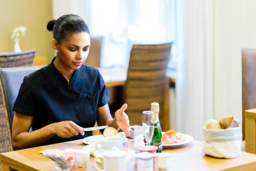 a woman sitting at a table eating food at Hotel-Résidence Am Klouschter in Mondorf-les-Bains