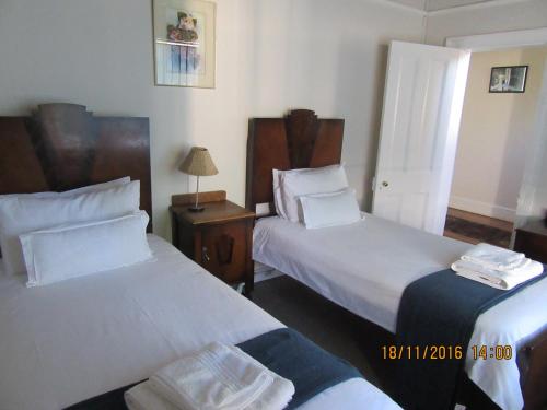 a hotel room with two beds and a table with a lamp at Thyme and Again Bed and Breakfast in Graaff-Reinet
