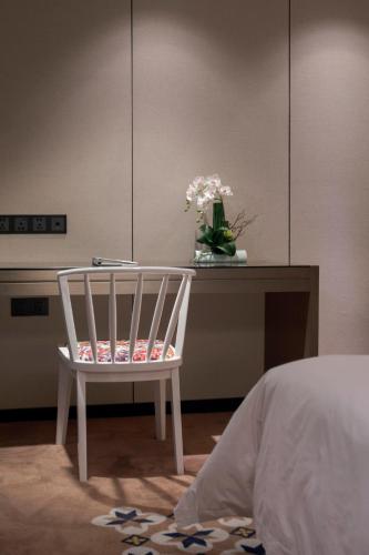 a white chair sitting next to a table with a vase of flowers at Paco Hotel Dongpu Guanghzou -Free Shuttle Bus for Canton Fair in Guangzhou