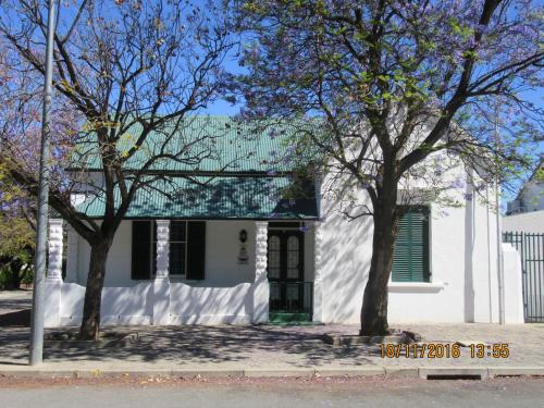a white house with a green roof and two trees at Thyme and Again Bed and Breakfast in Graaff-Reinet