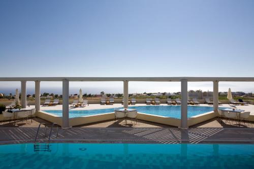 a view of a swimming pool with lounge chairs and a swimming pool at The Majestic Hotel in Fira
