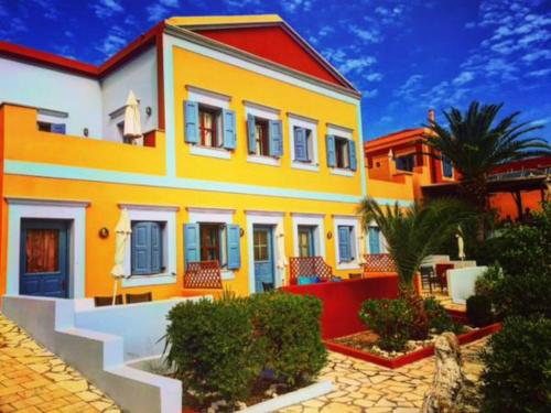 a large yellow and white house with trees and bushes at Taxiarchis in Symi