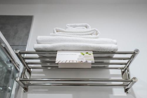 a towel rack with white towels in a bathroom at TOHOUSE Rooms in Turin