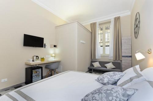 a white bedroom with a bed and a tv at TOHOUSE Rooms in Turin