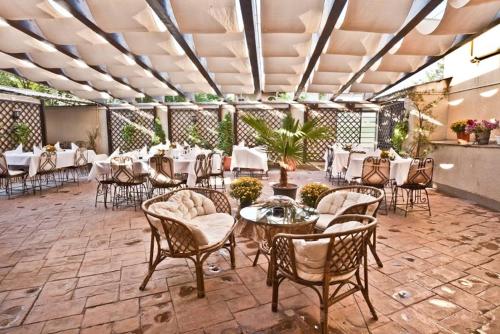 ブカレストにあるホテル イエスタデーの白いテーブルと椅子、テーブルサーチャー付きのレストラン
