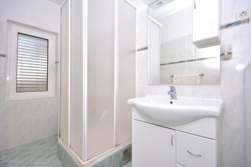 uma casa de banho branca com um lavatório e um chuveiro em Apartments Regina em Hvar