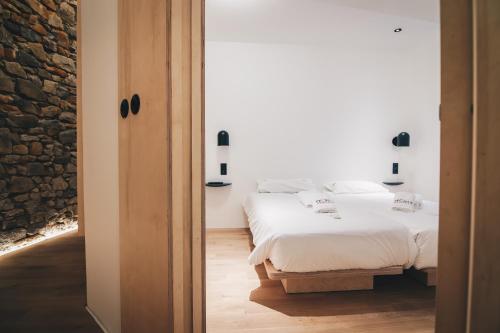 a bedroom with two beds and a stone wall at Moyua Apartment by People Rentals in Bilbao