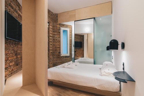 a bedroom with a white bed and a brick wall at Moyua Apartment by People Rentals in Bilbao