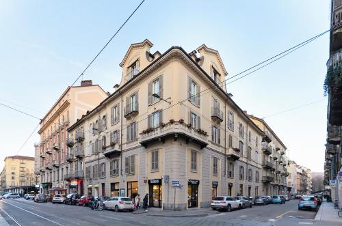 a large building on a city street with parked cars at TOHOUSE Rooms in Turin