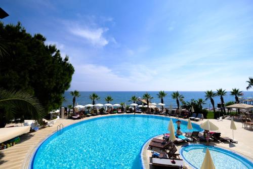 a swimming pool with chairs and umbrellas and the ocean at Anitas Hotel in Konaklı