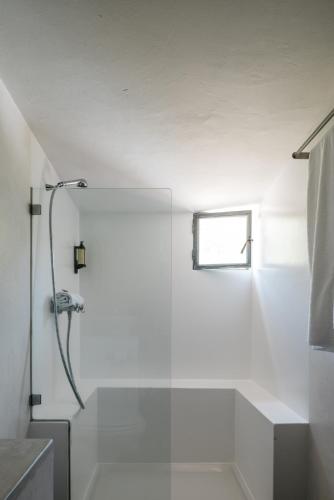 a white bathroom with a shower and a window at Tres Marias in Vila Nova de Milfontes