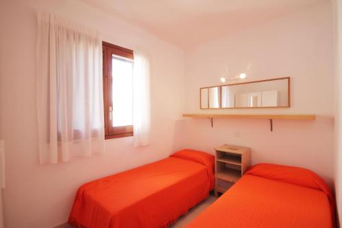 2 orangefarbene Betten in einem Zimmer mit Fenster in der Unterkunft Apartment Carmen in L'Escala