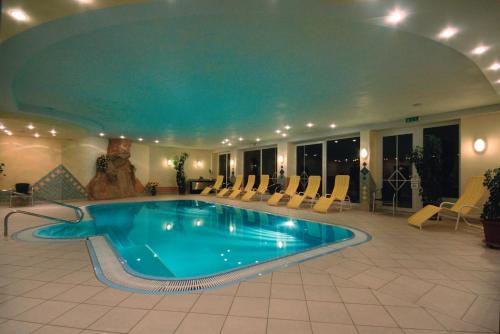 ein großer Swimmingpool in einem Hotel mit Stühlen drum herum in der Unterkunft Hotel Styrolerhof in Steeg
