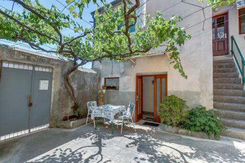a table and chairs in front of a house at Apartments Ivna in Veli Lošinj