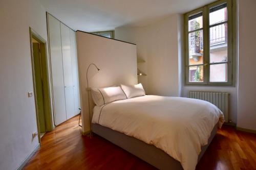 a bedroom with a large white bed with a window at Via Sambuco in Iseo