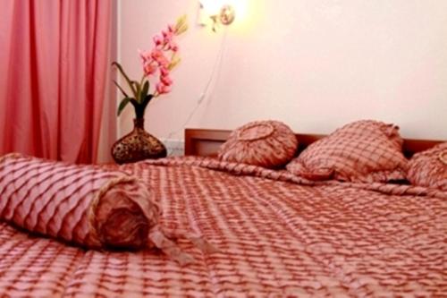 a bed with a red comforter and pillows on it at Edem Hotel in Chişinău