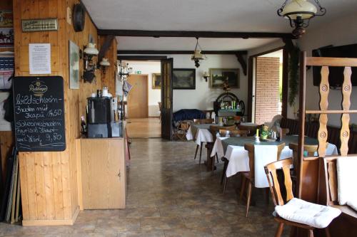 a restaurant with tables and chairs and a chalkboard at Landhotel "Zum ersten Siedler" in Brieselang