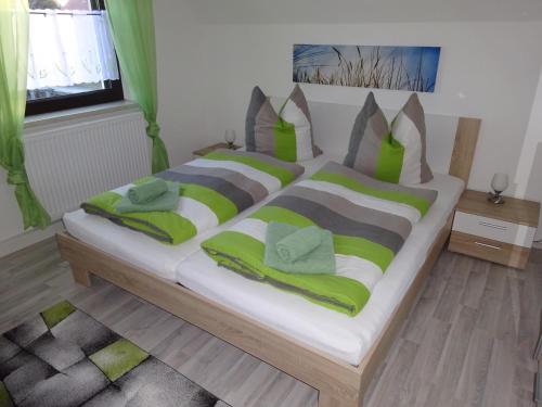 ein Schlafzimmer mit einem großen Bett mit grünen und grauen Kissen in der Unterkunft Ferienhaus Oberlausitz in Malschwitz