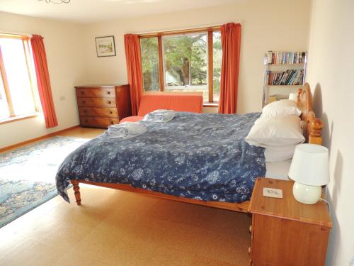 1 dormitorio con 1 cama y 1 mesa con lámpara en Atlantic Bay Cottage, en Clachan