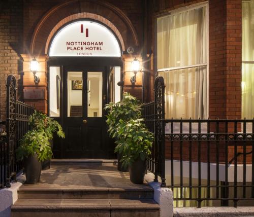 a front door of a building with two potted plants at Nottingham Place Hotel in London