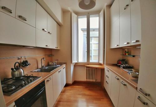 a kitchen with white cabinets and a sink and a window at Domus Orvieto in Orvieto