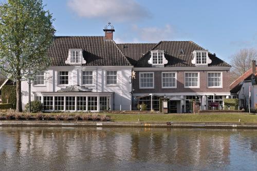 a large white house next to a body of water at De Nederlanden, Restaurant & Boutique Hotel in Vreeland