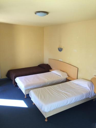two beds in a room with white sheets at Hôtel & Résidence Avermes in Avermes