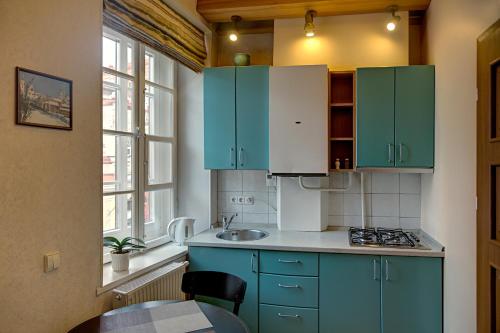 a kitchen with blue cabinets and a sink and a table at Bernardinu B&B House in Vilnius