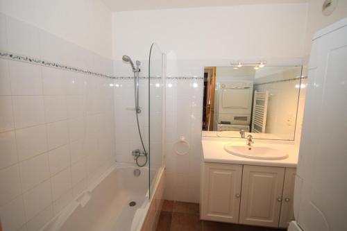 uma casa de banho com um lavatório e um chuveiro com um espelho. em Chalet la Forestière em Orcières