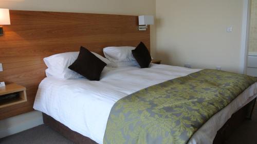 a large bed with white sheets and black pillows at Ramsey Park Hotel in Ramsey