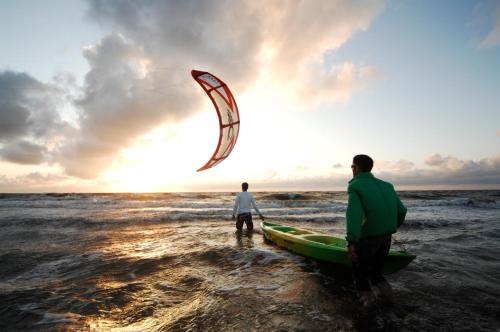 two men standing on the beach with a kite at Hotel Strandhof in Baltrum