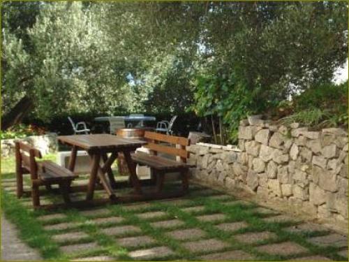 a picnic table and two chairs and a stone wall at Apartments Vrisika-family apartment in Makarska