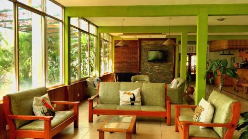 a living room with a couch and chairs and windows at Hotel Carmen in Puerto Iguazú