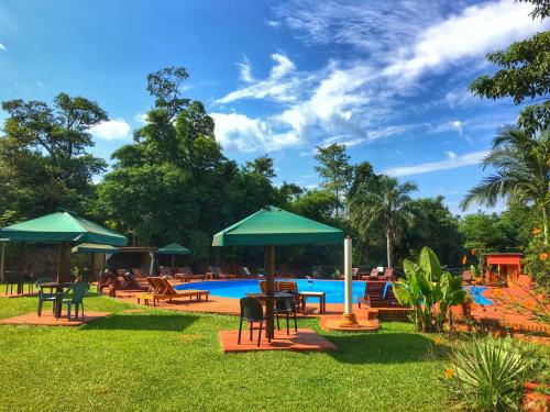a pool with tables and chairs and umbrellas at Hotel Carmen in Puerto Iguazú