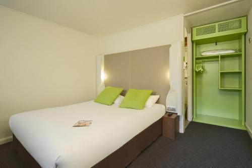 een slaapkamer met een groot wit bed met groene kussens bij Kyriad Sannois - Ermont in Sannois