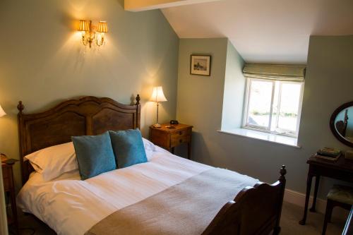 a bedroom with a bed with blue pillows and a window at The Lion in Leintwardine