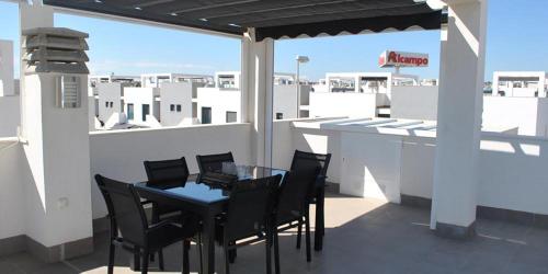a patio with a table and chairs on a roof at OasisBeach Penthousse la Zénia in Playas de Orihuela