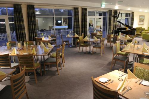 a restaurant with wooden tables and chairs and windows at Ramsey Park Hotel in Ramsey