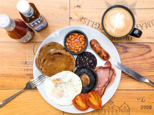 um prato de comida de pequeno-almoço com ovos, bacon e uma chávena de café em Bear and Ragged Staff em Oxford