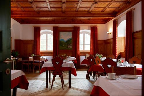 ein Esszimmer mit Tischen und Stühlen mit rotem Tischtuch in der Unterkunft Hotel Dolomitenhof & Chalet Alte Post in Sexten