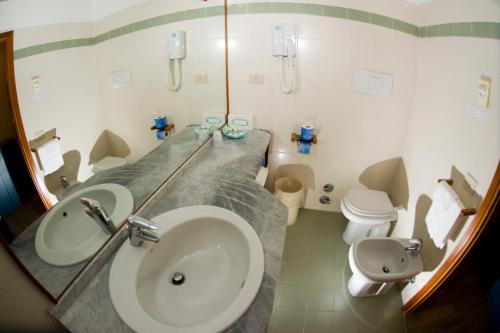 a bathroom with a sink and a toilet and a mirror at Hotel Select in Marina di Campo