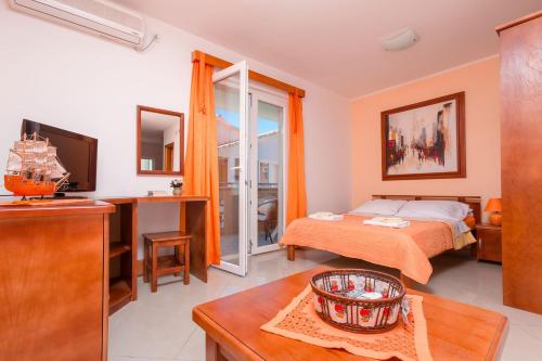 a bedroom with a bed and a desk and a television at Rosić Apartments in Tivat