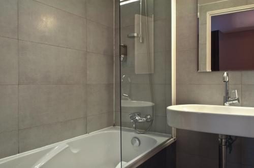 y baño con ducha, lavabo y bañera. en Hôtel Eugénie, en París
