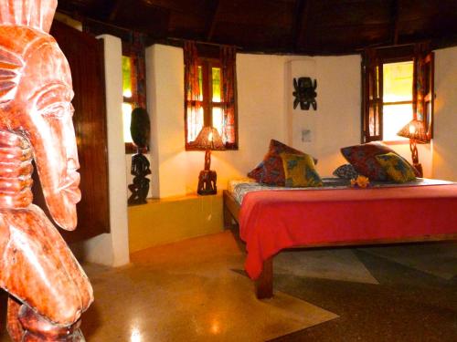 a bedroom with a bed in a room with windows at Ankobra Beach Resort in Axim